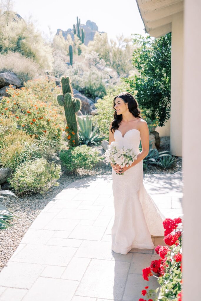 Bride during spring wedding, looking off into desert landscape, while holding bouquet.