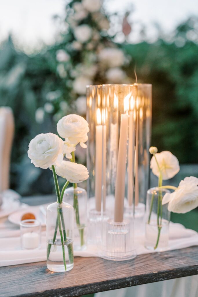 Bud vases with white floral and taupe pillar candlesticks.