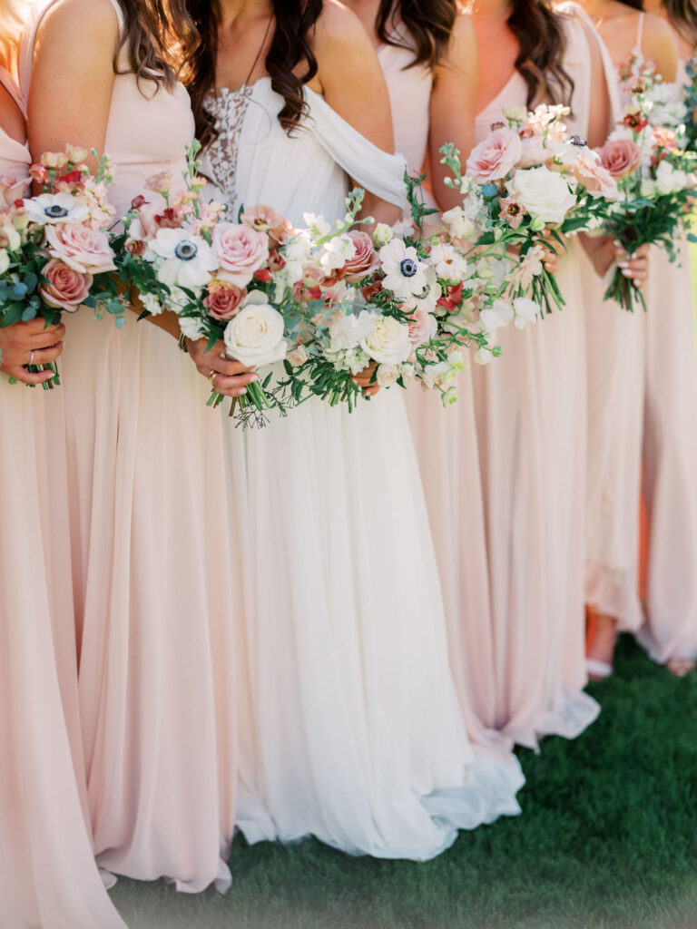 Bridal bouquet and bridesmaid bouquets held by bride and bridesmaids. Bridesmaids in blush dresses.