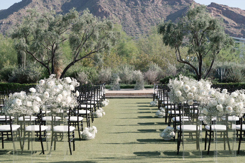 Outdoor wedding reception at El Chorro with mountain background and white roses and baby's breath floral arrangements.