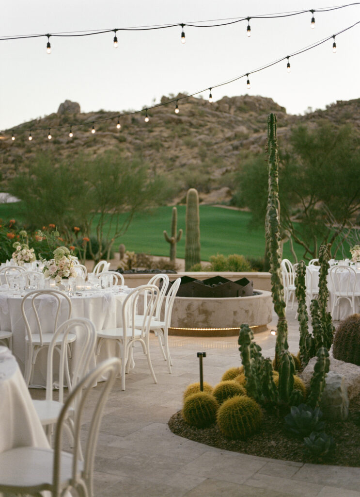 Outdoor wedding reception space at Estancia with white tables and white and blush floral and desert landscapes.