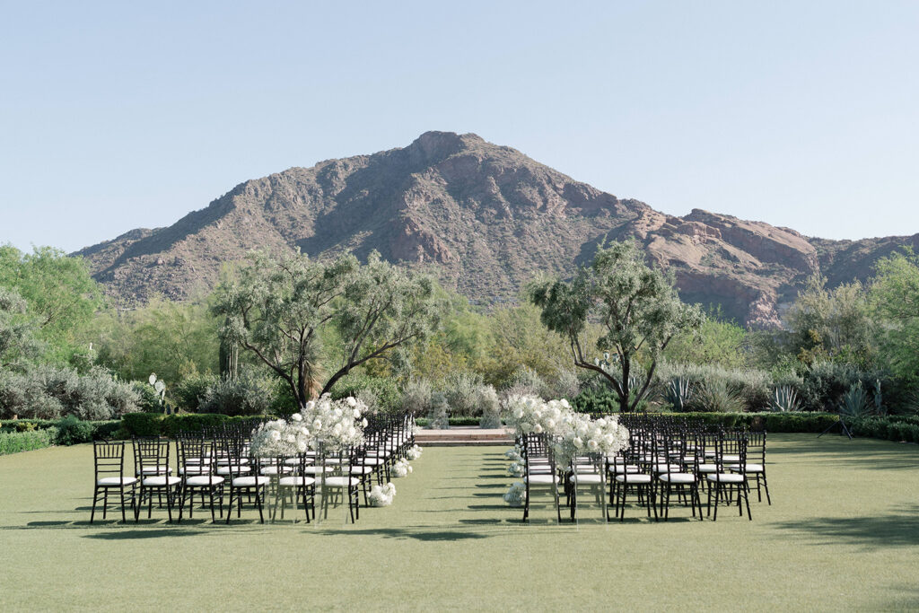 Outdoor wedding reception at El Chorro with mountain background and white roses and baby's breath floral arrangements.