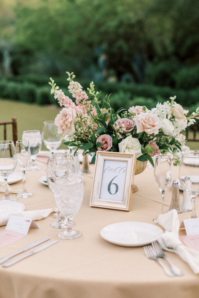 Wedding reception table with gold frame table number and pink and white floral centerpiece.