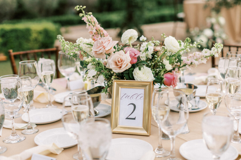 Wedding reception table with gold frame table number and pink and white floral centerpiece.