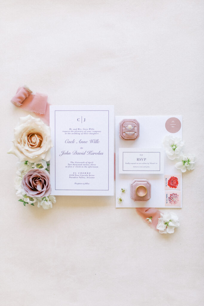 Wedding invitation of white and pink color palette and floral details and pink ribbon details around them.