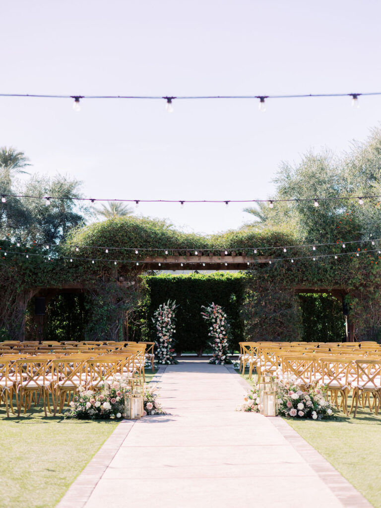 Outdoor wedding ceremony space at Wigwam Resort with floral pillars at altar space and back of aisle ground flowers arrangements.