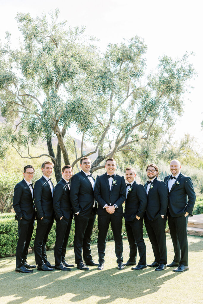 Groom and groomsmen in black suits standing in a row.