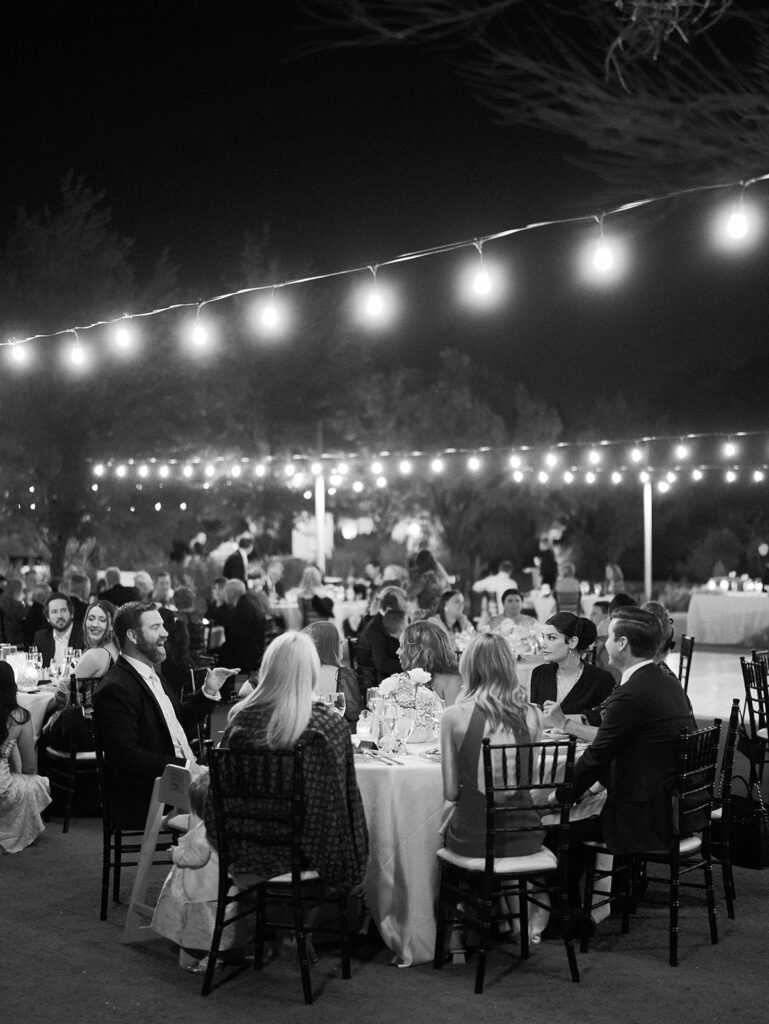 Outdoor reception at El Chorro under string lights of round tables.