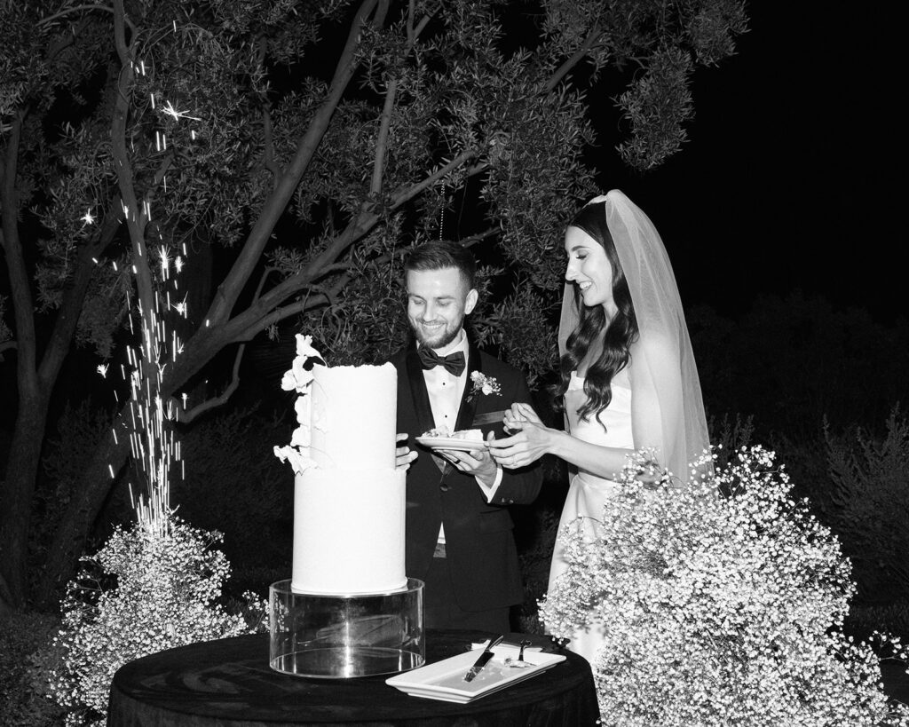 Bride and groom cutting white cake at wedding reception.