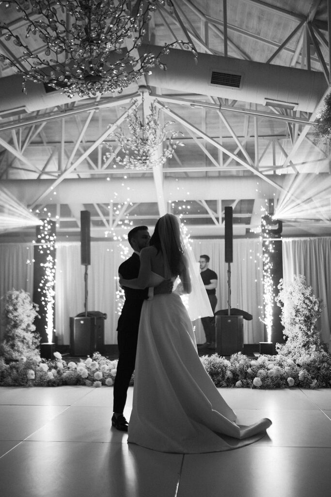 Bride and groom dancing on indoor dance floor at wedding reception.