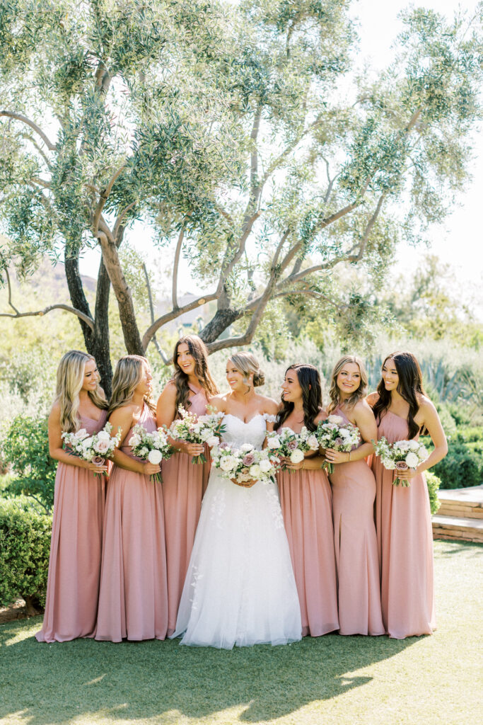 Bride standing in row with bridesmaids wearing blush bridesmaid dresses.