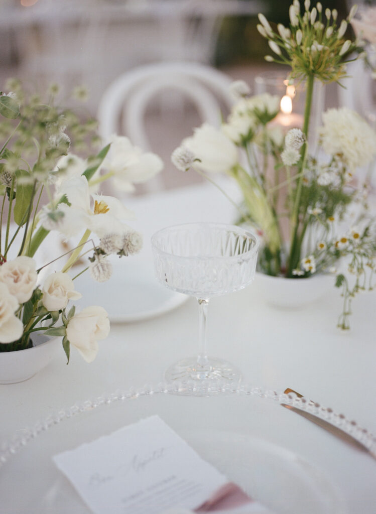 Wedding reception table with glass glass and plate and unique centerpieces.