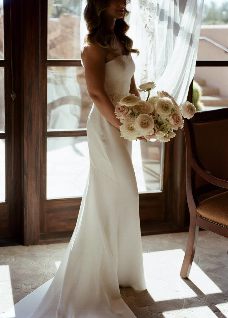 Bride holding lush bridal bouquet of white and blush roses.