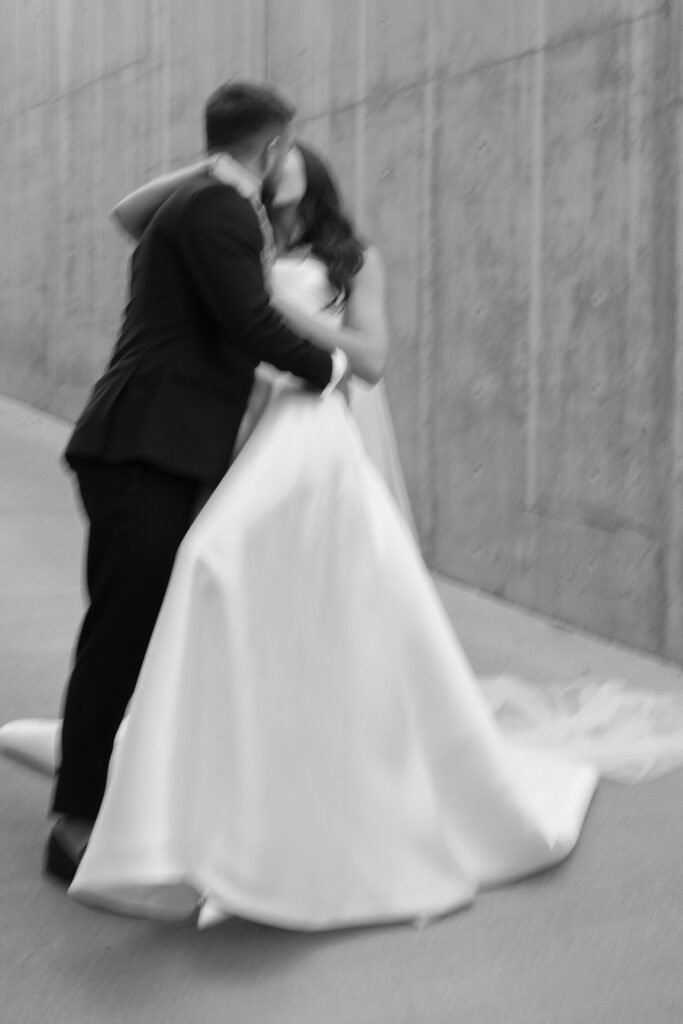 Blurred photo of groom kissing bride and dipping her back while holding on.