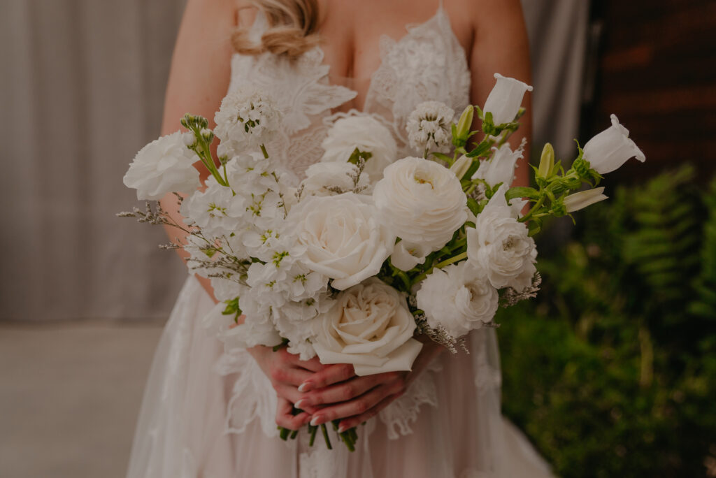 White flowers bridal bouquet of roses, ranunculus, and other white flowers.