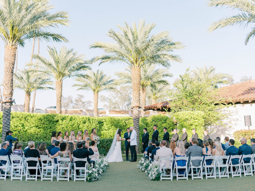 Outdoor wedding ceremony with guests seated and wedding party standing at front and bride and groom in center with officiant at Scottsdale Resort.