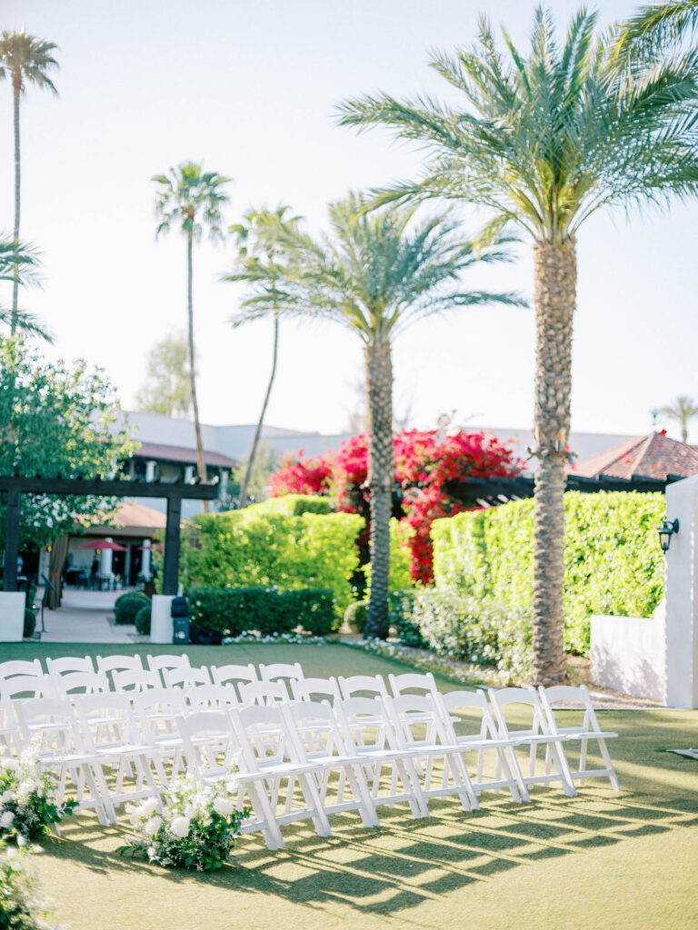 Outdoor wedding ceremony at Scottsdale Resort with white folding guest chairs and aisle ground arrangements.