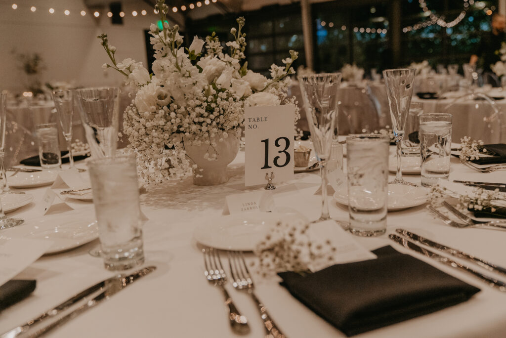 Wedding reception table with white flowers centerpiece in white vase.