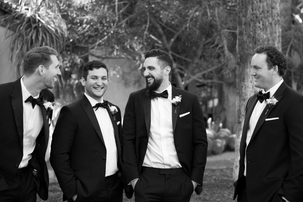 Groom laughing with groomsmen all in black suits.