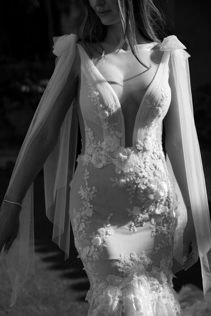 Modern mermaid chic bridal gown worn by bride with shoulder ties and deep front v cut.
