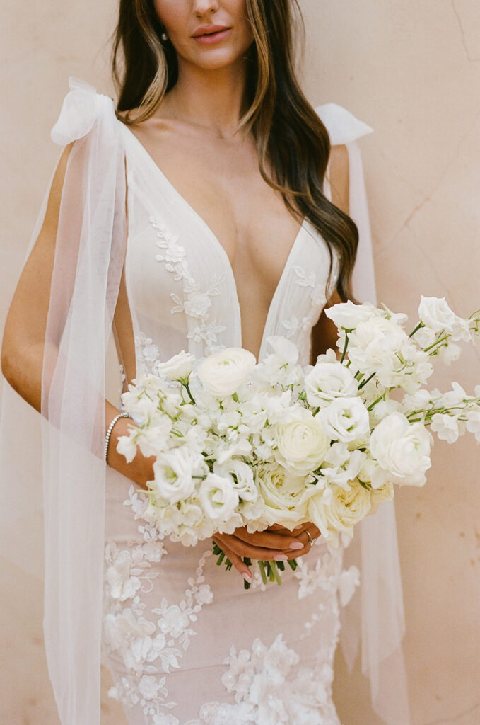 Lush bridal bouquet of white flowers held by bride.