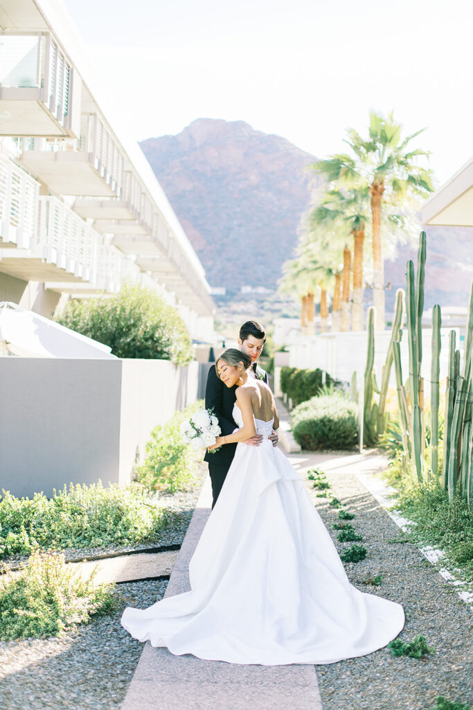 Bride and groom standing on paved walkway embracing at Mountain Shadows.