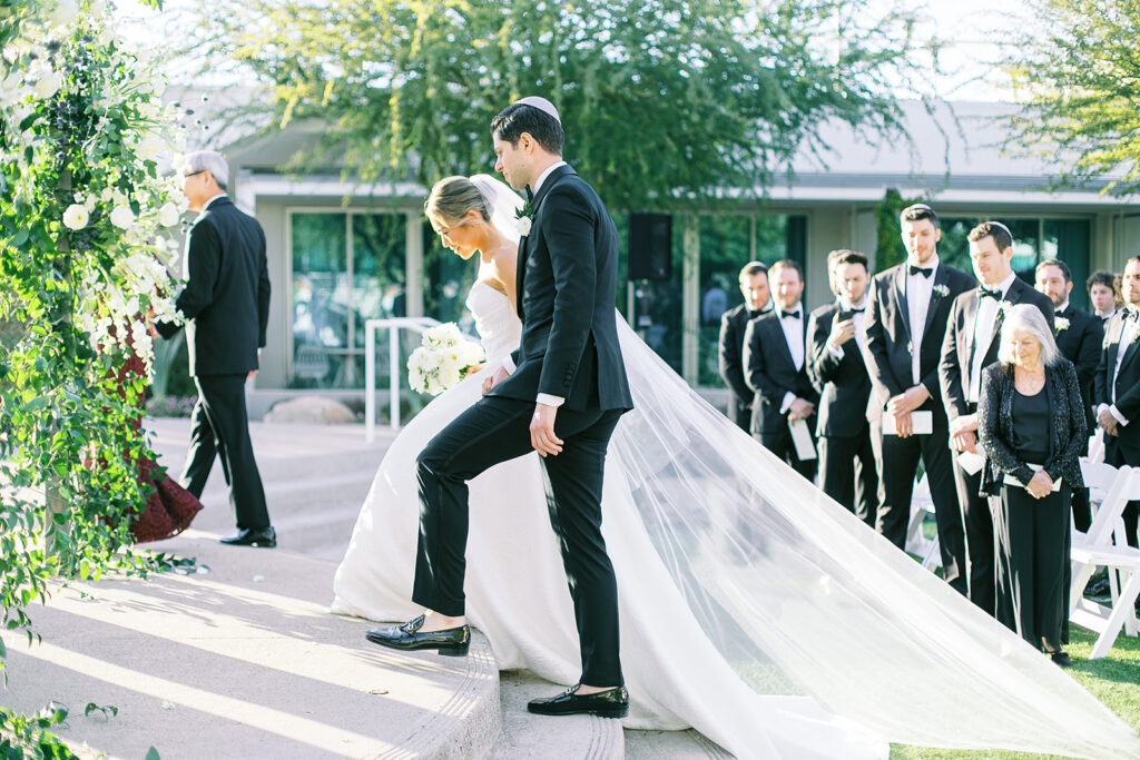 Bride and groom holding hands, walking up wedding ceremony steps to altar space.