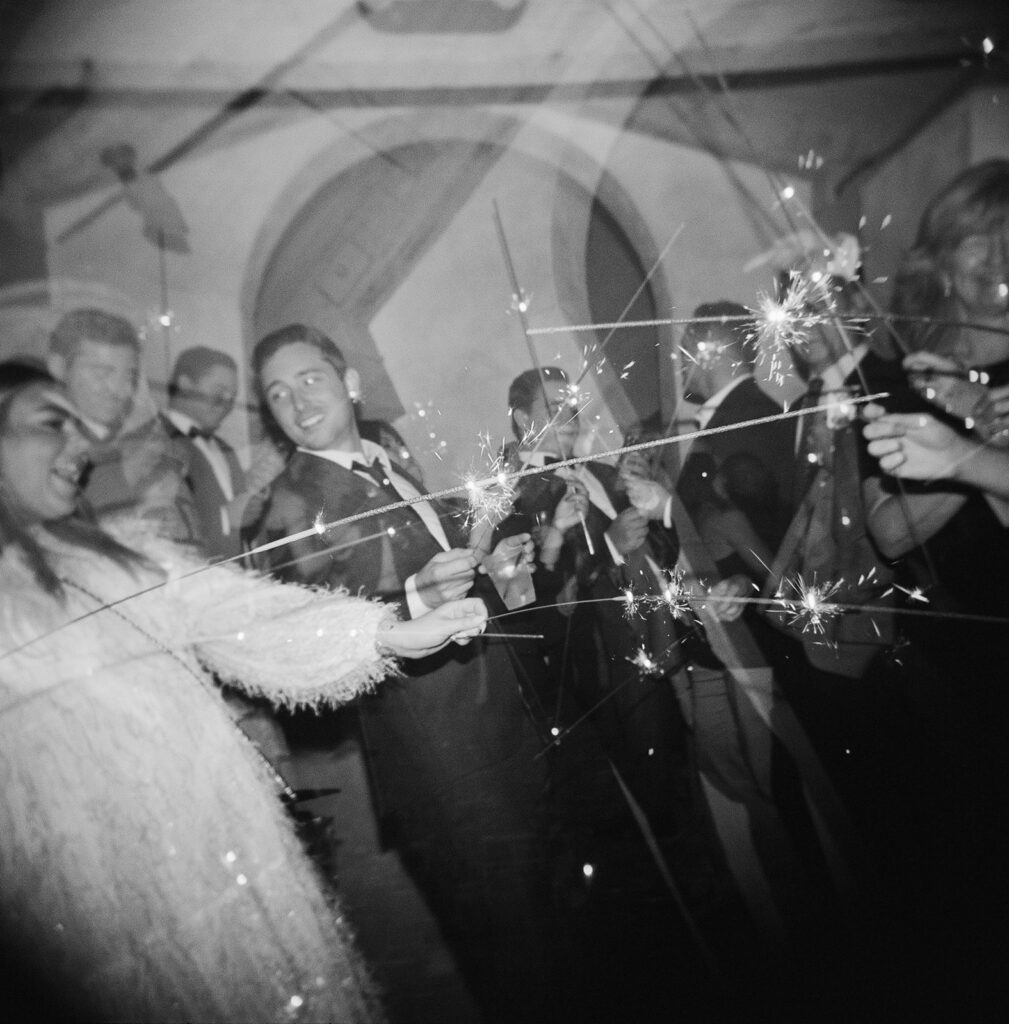 Guests holding sparklers at wedding reception.