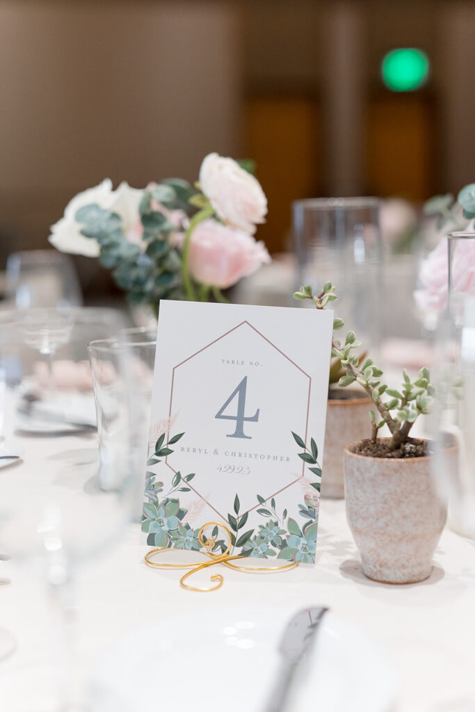 Custom wedding reception table number with greenery and succulent design on reception table with succulents and floral centerpieces.