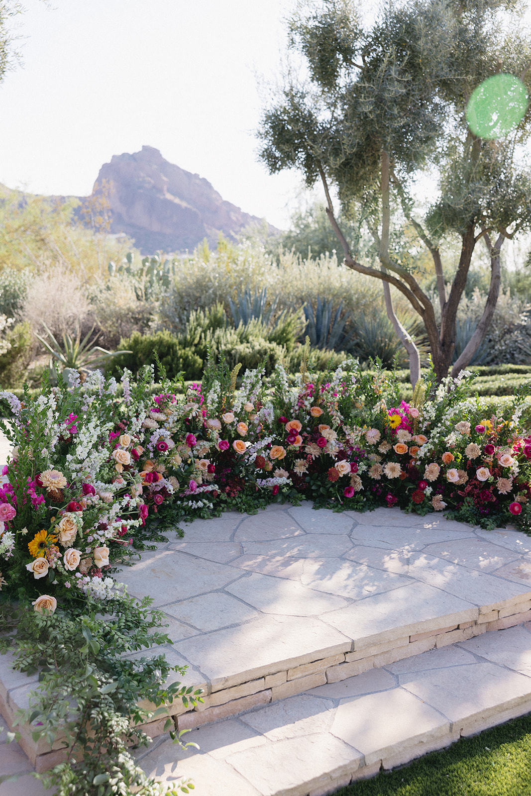 Wedding ceremony ground arc in altar space of colorful pink, peach flowers and greenery at El Chorro.