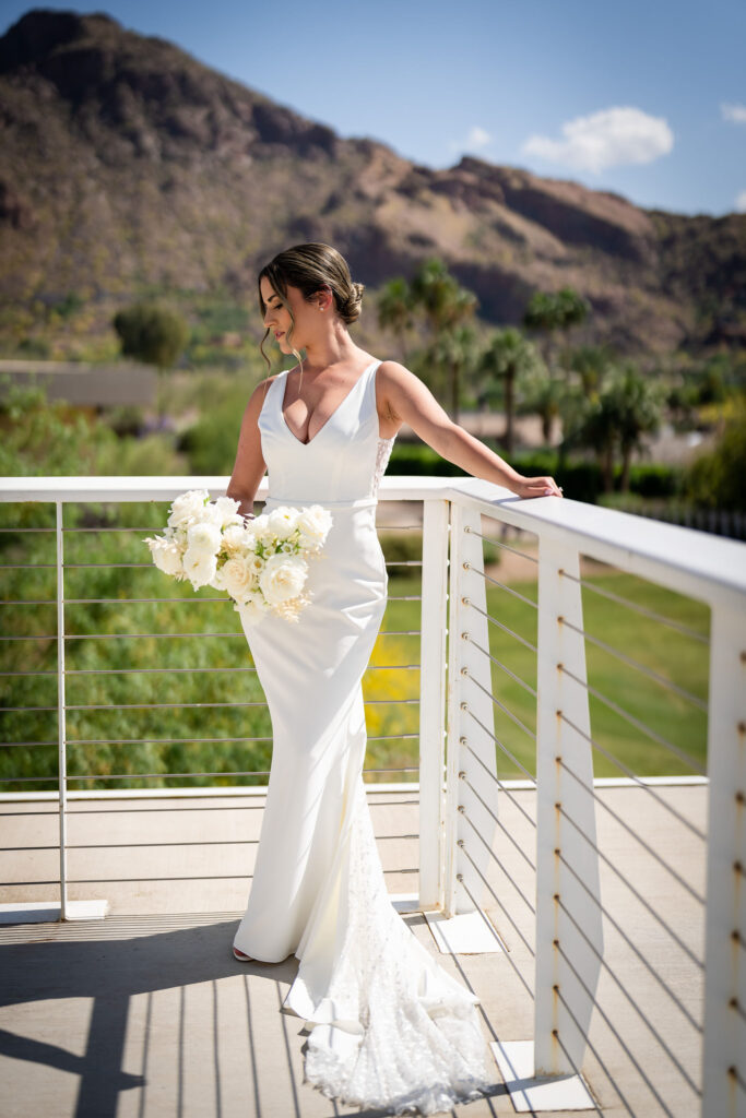 Bride standing in corner of patio railing at Mountain Shadows with Camelback Mountain in the background.