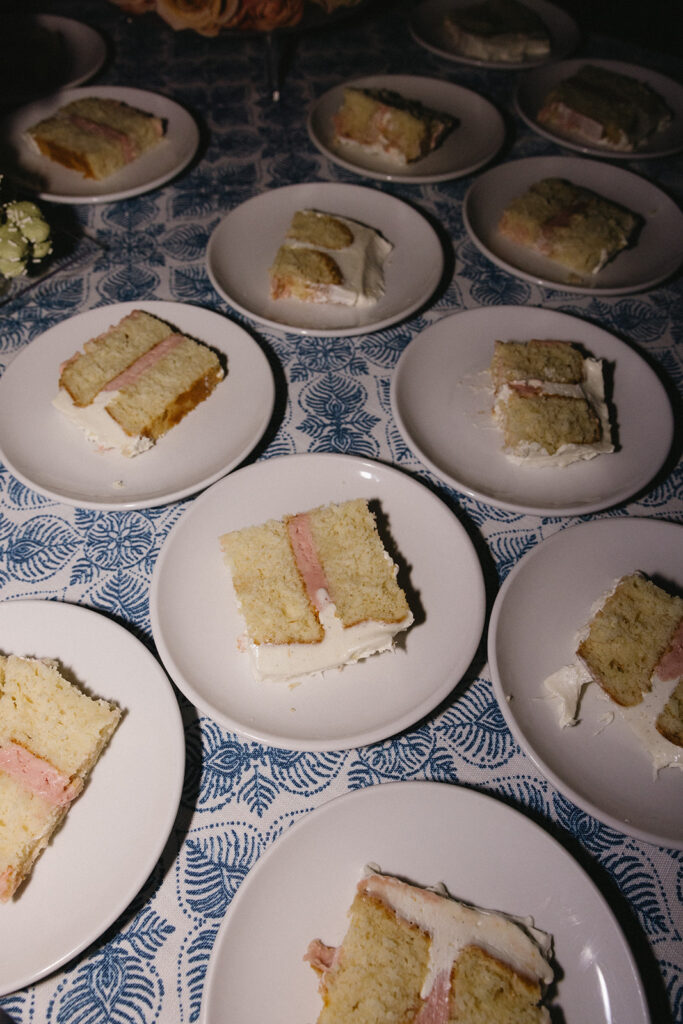 Wedding cake slices on white plates on blue pattern tablecloth.