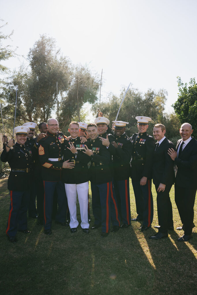 Groom with groomsmen and men in wedding party wearing military dress or black suits.