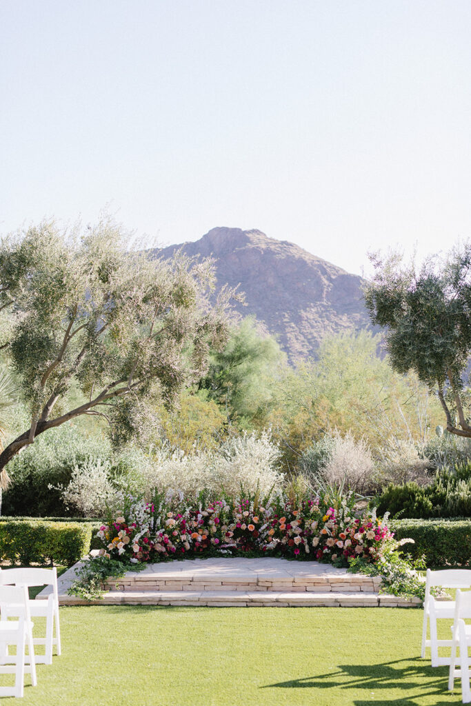 Wedding ceremony ground arc in altar space of colorful pink, peach flowers and greenery at El Chorro.