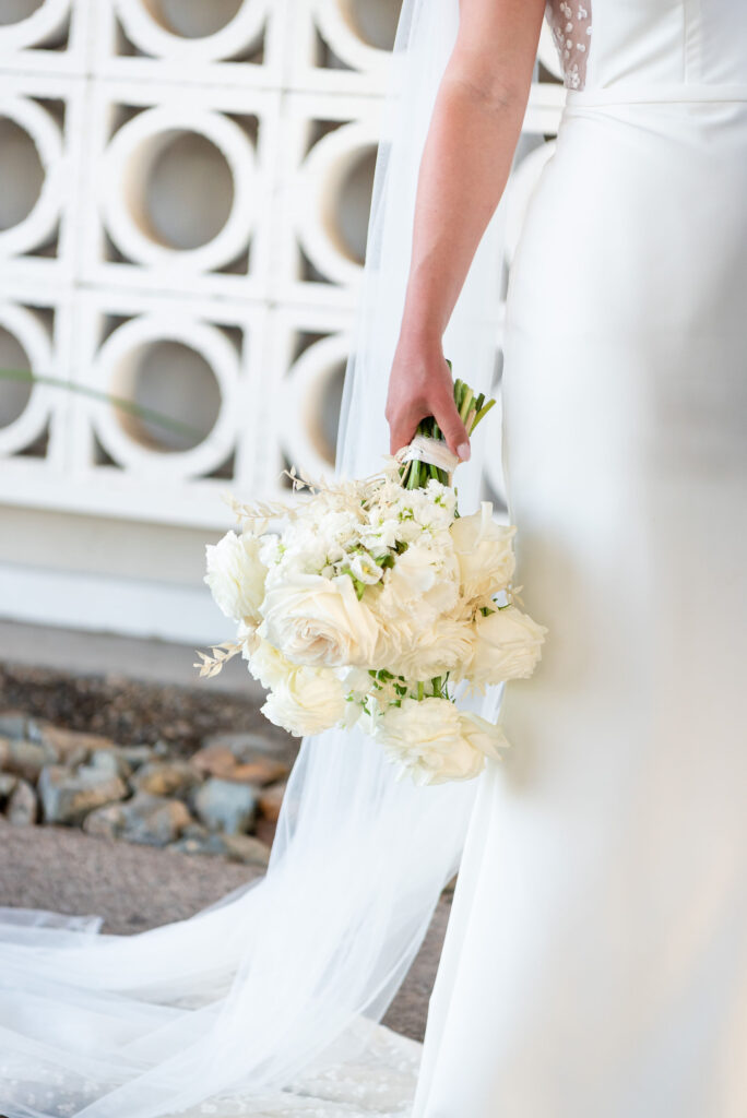 Bride holding bouquet down to her side of white flowers.