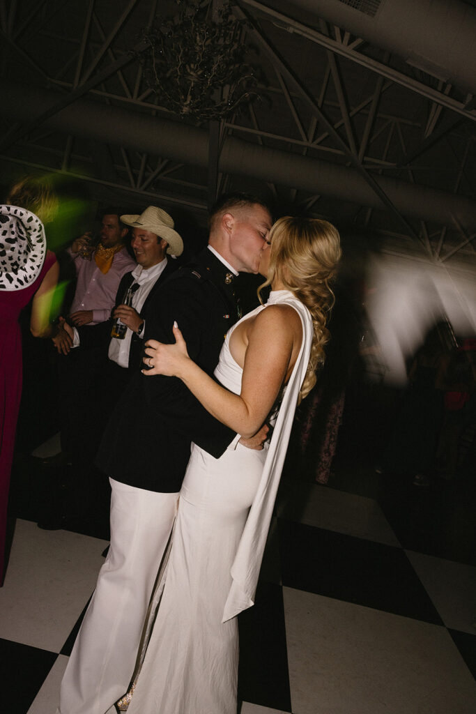 Bride and groom kissing on dance floor at wedding reception.
