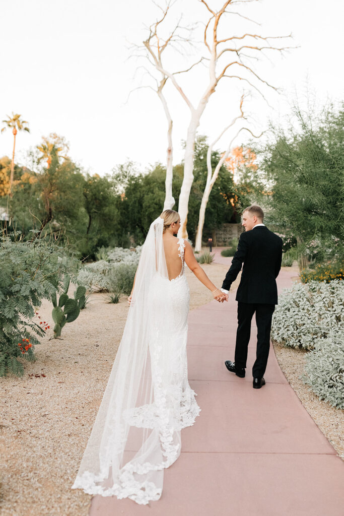 Bride and groom walking down path holding hands at Arizona Biltmore.