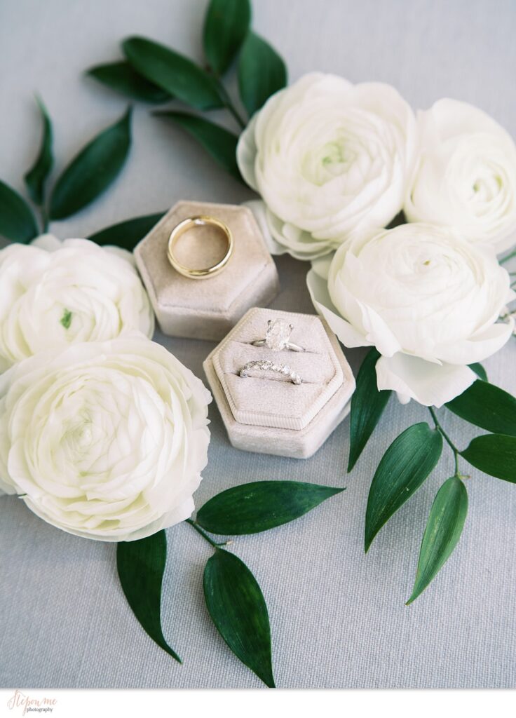 Bride and groom rings detail image with white ranunculus flowers.