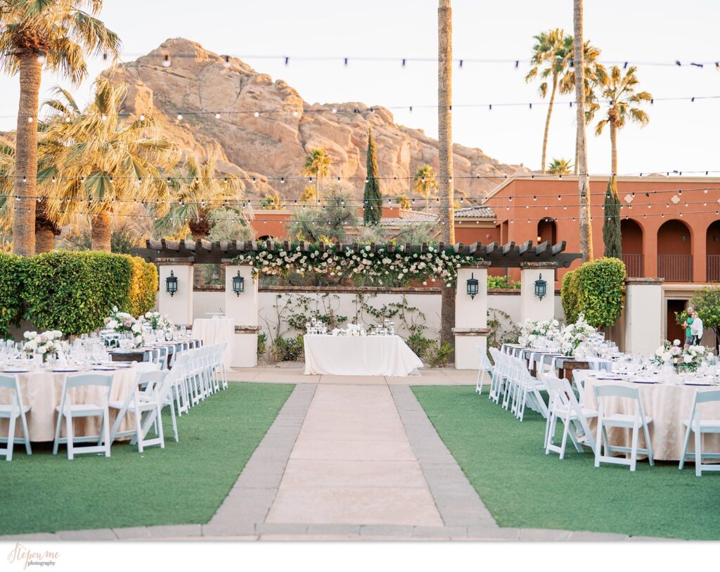 Outdoor wedding reception space with long and round reception tables and a sweetheart table under Omni resort pergola.