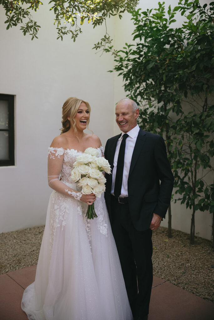 Bride standing with man in black suit, laughing.