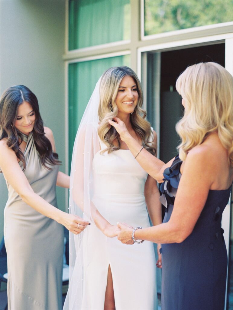 Bride receiving help getting ready from two women.