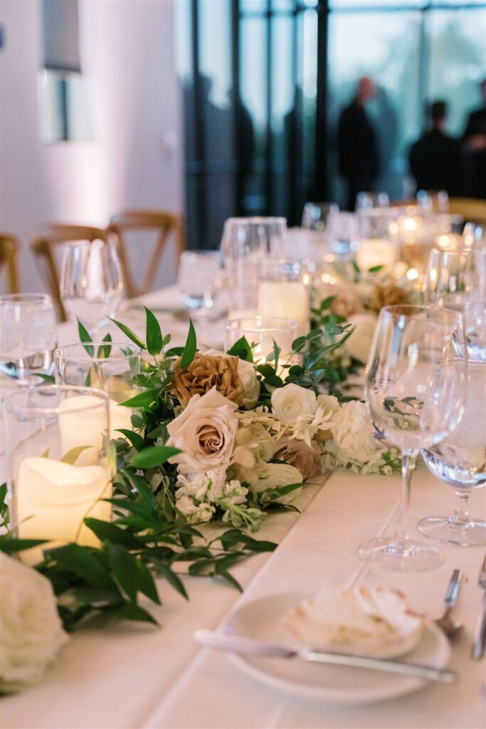 Long reception table garland of greenery and floral and candles.