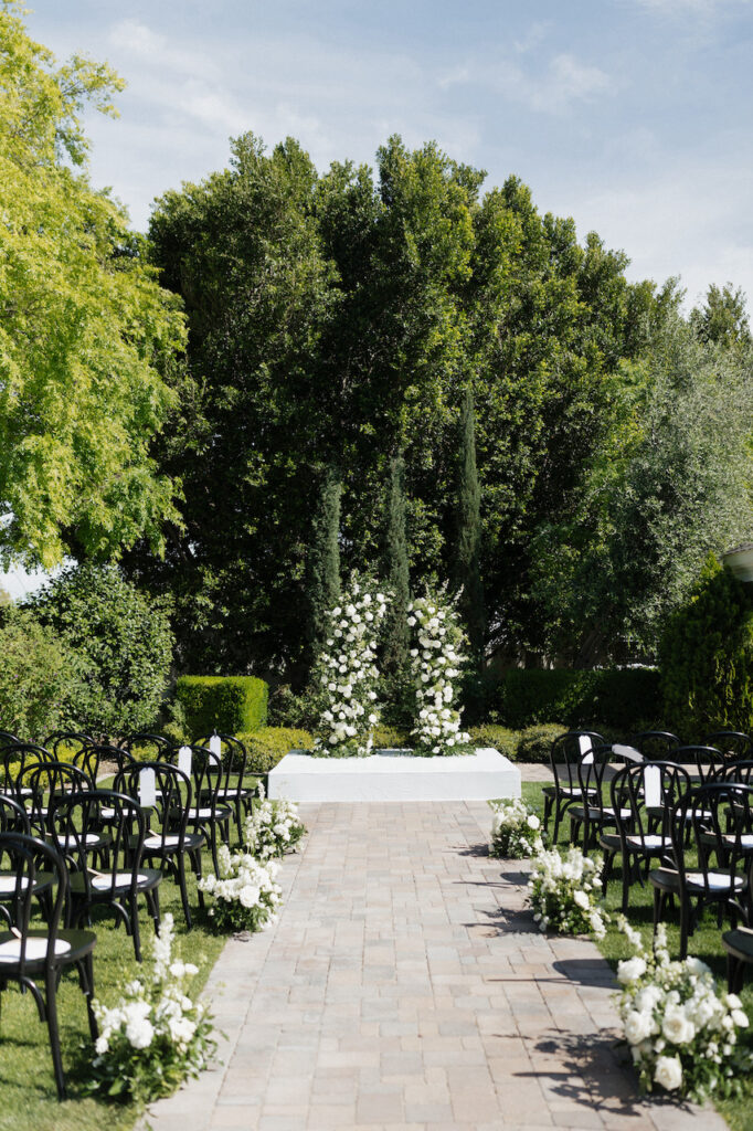 Two floral pillars for wedding ceremony altar space of white flowers and greenery.