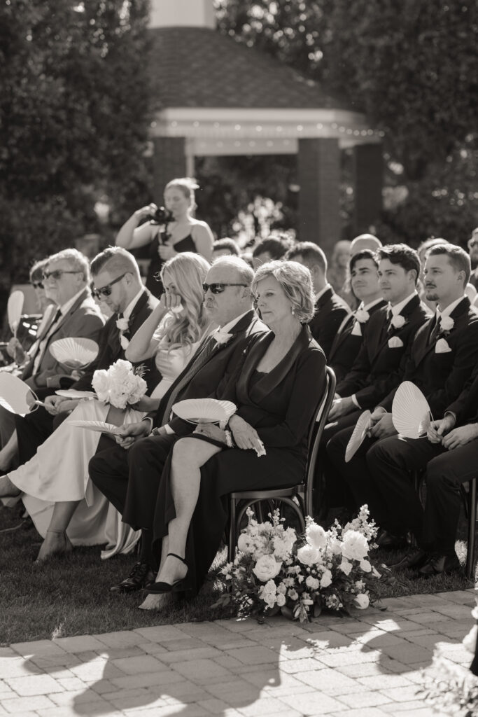 Wedding guests seated at outdoor wedding ceremony with aisle ground floral.