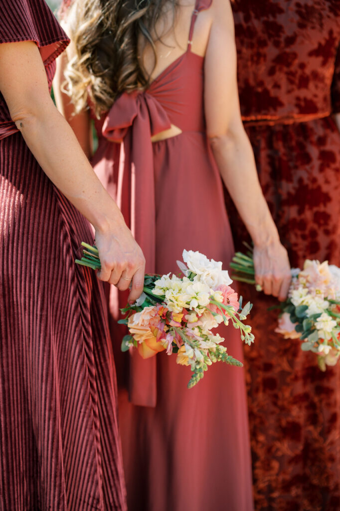 Bridesmaids holding bouquets, wearing red dresses.