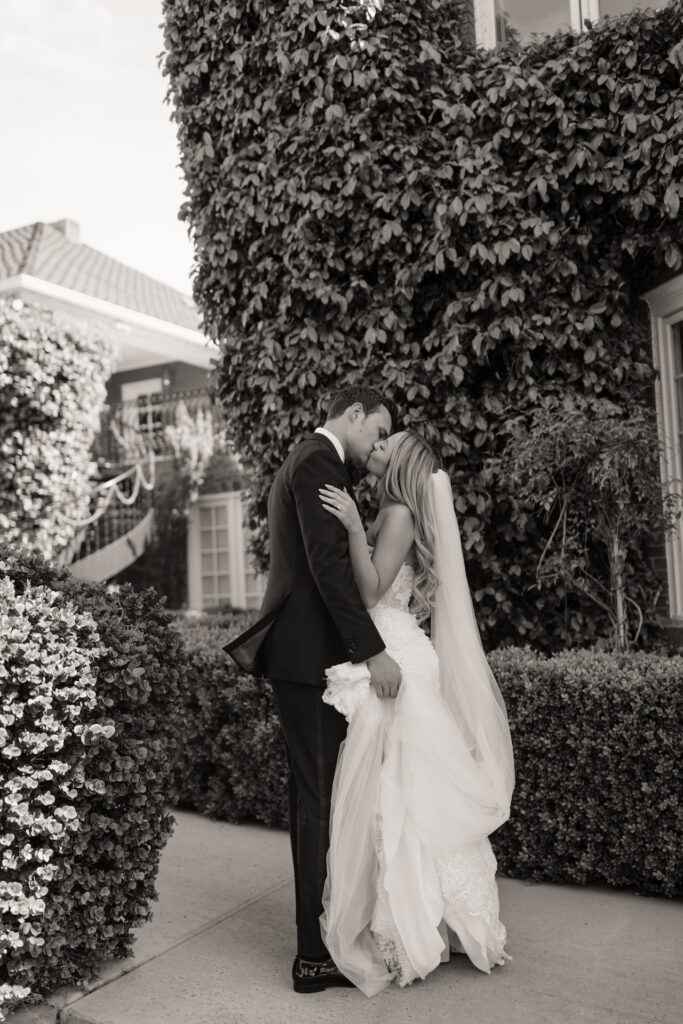 Bride and groom kissing and embracing at Stonebridge Manor venue buildings.