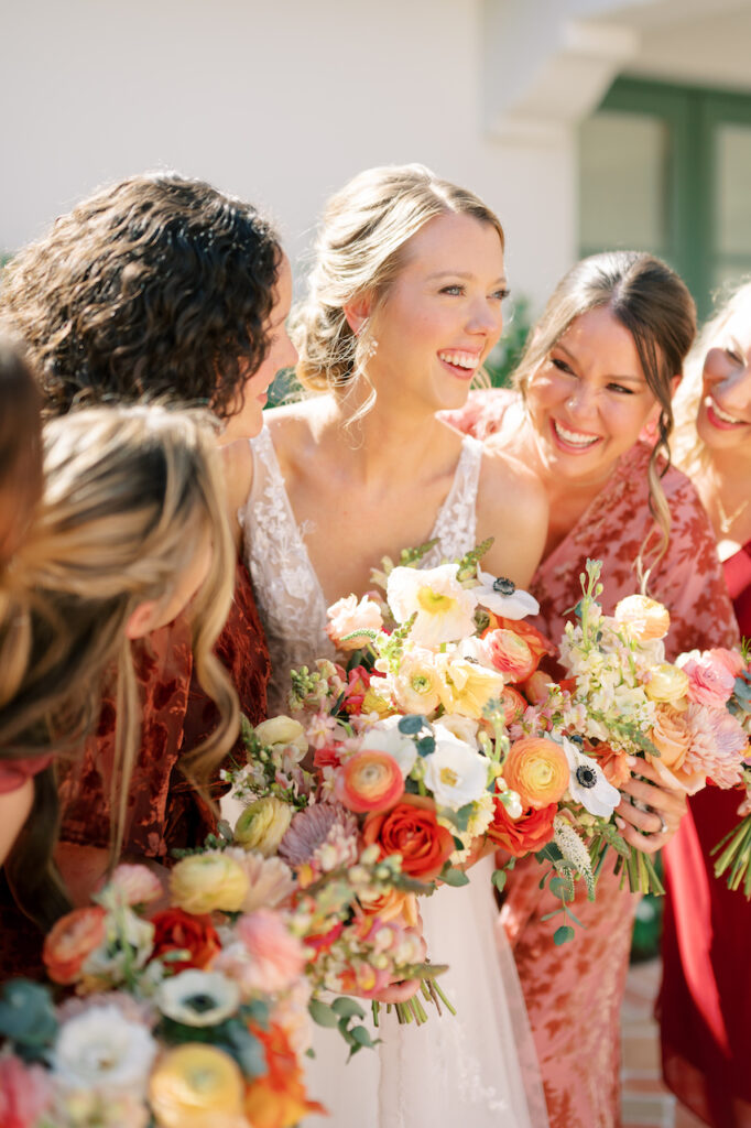Bride smiling with bridesmaids, all holding bouquets.