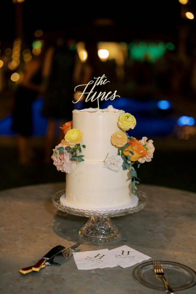 Two tiered white wedding cake with added flowers.