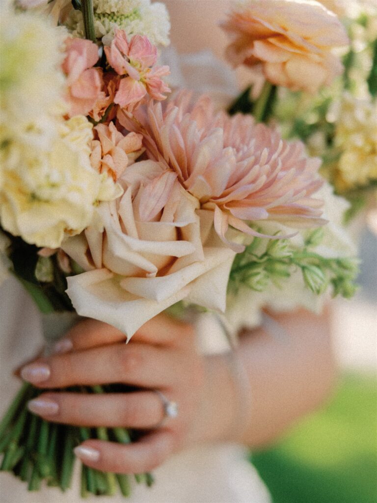 Detail photograph of wedding bouquet with pink, yellow, peach, and white flowers.