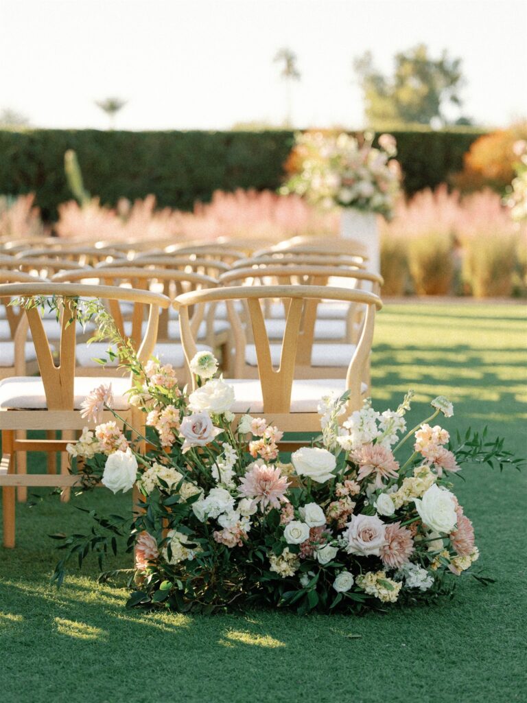 Back of outdoor ceremony aisle ground floral of pink, white, and yellow colors with greenery.